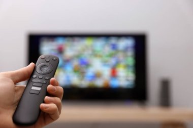 Televizyonda uzaktan kumandayla kanal değiştiren bir kadın. Metin için boşluk