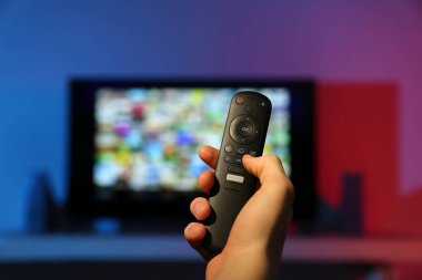 Televizyonda uzaktan kumandayla kanal değiştiren kadın, yakın çekim.