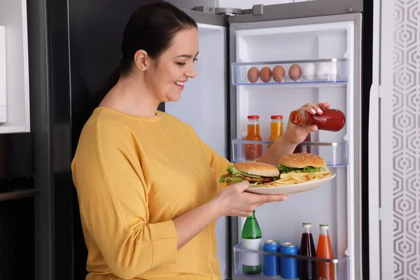 Šťastná Nadváha Žena Kečupem Hamburgery Blízkosti Lednice Kuchyni — Stock fotografie