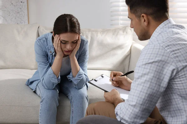 Unhappy young woman having session with her therapist indoors