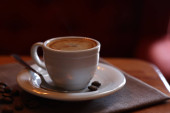 Šálek horké aromatické kávy a pražených fazolí na dřevěném stole v kavárně. Mezera pro text