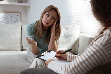 Mutsuz genç bir kadın terapistiyle içeride görüşüyor.