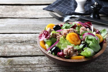 Bir kase lezzetli salata, konserve ton balığı ve sebzeler ahşap masada, mesaj için yer var.