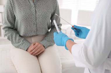Doktor, klinikteki kadından cinsel yolla bulaşan hastalık testi için örnek alıyor.
