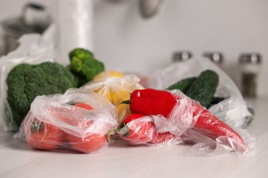 Plastik torbalar ve beyaz masada taze ürünler.