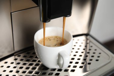 Espresso makinesi fincana kahve dolduruyor, yakın plan.