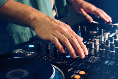DJ, gece kulübünde modern konsol karıştırıcısında müzik yaratıyor.