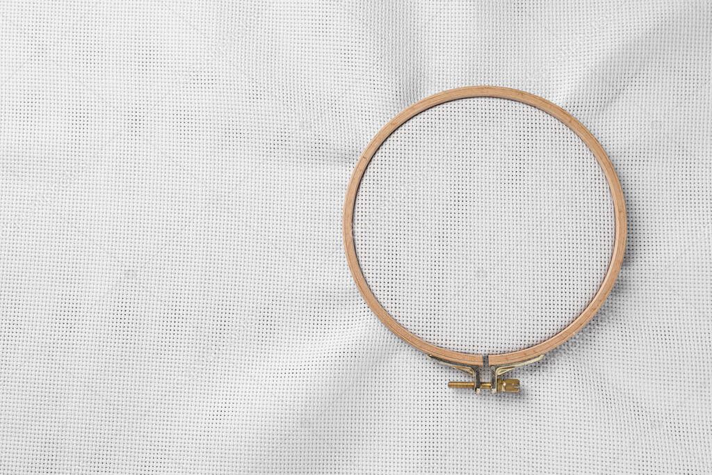 Embroidery hoop with white fabric stretched as background, top view. Space for text