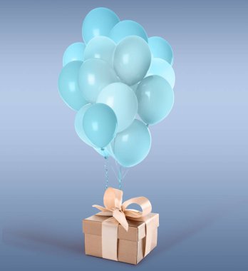 Güzel hediye kutusu ve açık mavi arka planda bir sürü balon.