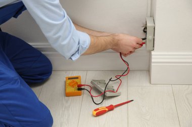 Elektrikçi ve testçi içeride voltajı kontrol ediyor, yakın plan.