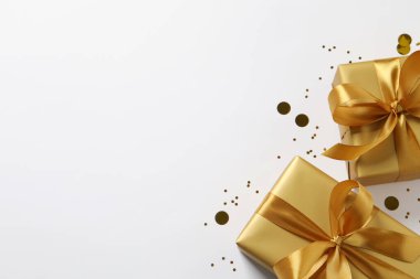 Güzel altın hediye kutuları ve beyaz arka planda konfeti, düz yatış. Metin için boşluk