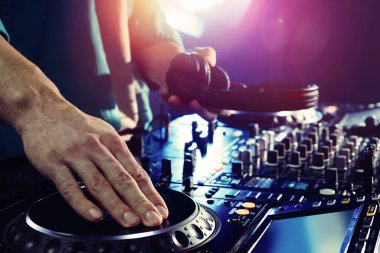 DJ, gece kulübünde modern konsol karıştırıcısında müzik yaratıyor.