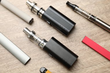 Tahta masada farklı elektronik sigaralar, düz yatış. Sigara alternatifi