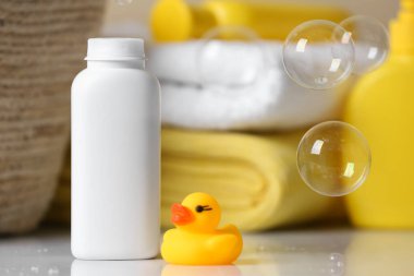 Bir şişe toz tozu ve plastik ördek beyaz masada, mesaj için yer var. Bebek kozmetik ürünü