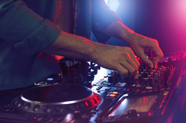 DJ, gece kulübünde modern konsol karıştırıcısında müzik yaratıyor.