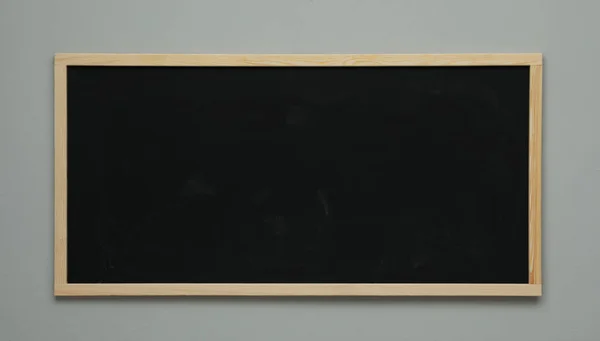 灰色墙上挂着干净的黑色黑板 — 图库照片