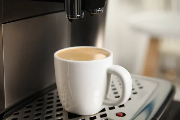 Espresso machine with cup of fresh coffee on drip tray against blurred background, closeup