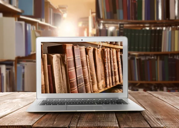 在线图书馆 木制桌子上的现代笔记本电脑和在室内放书的架子 — 图库照片