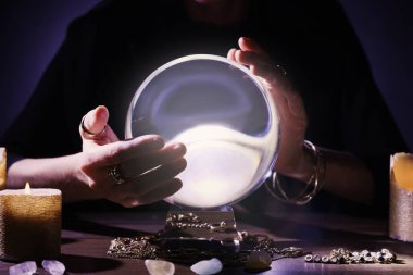 Kahin, kristal küreyi kullanarak karanlıkta geleceği tahmin ediyor. Yakın plan. Falcı.