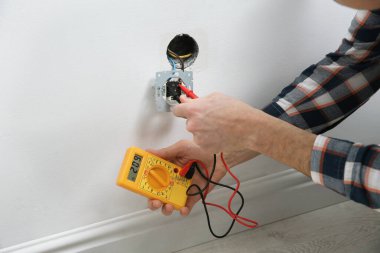 Elektrikçi ve testçi içeride voltajı kontrol ediyor, yakın plan.