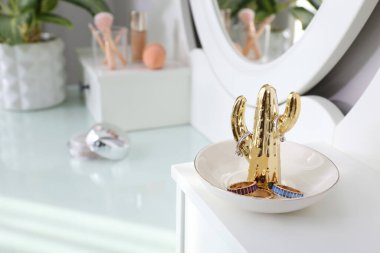 Beyaz tuvalet masasında şık bijouterie ile kaktüs şekilli tutucu, yakın plan. Metin için boşluk