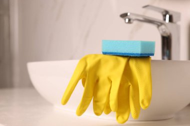 Banyo lavabosundaki sünger ve lastik eldivenler kapalı, yakın plan. Metin için boşluk