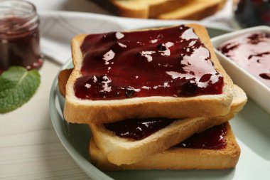 Beyaz ahşap masada servis edilen reçelli leziz tostlar, yakın plan.