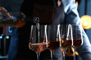 Barmen şişeden cam içine gül şarabı dolduruyor, yakın plan.