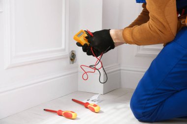 Elektrikçi ve testçi içeride voltajı kontrol ediyor, yakın plan.