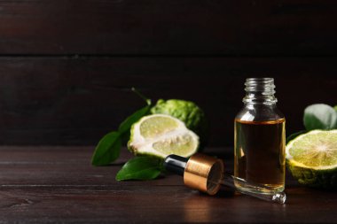 Bir şişe temel yağ, pipet ve ahşap masada taze bergamot meyveleri. Metin için boşluk