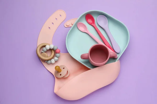 Set Plastic Dishware Silicone Bib Baby Accessories Violet Background Flat — Stock Photo, Image
