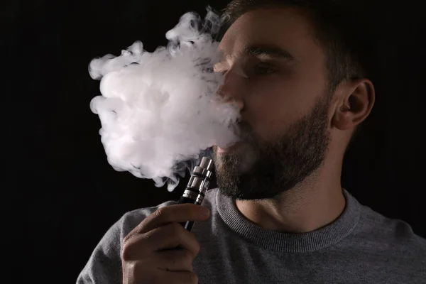 Mann Benutzt Elektronische Zigarette Auf Schwarzem Hintergrund — Stockfoto