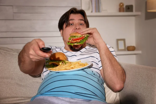 Nadwaga Człowiek Talerzem Hamburgerów Frytki Oglądanie Telewizji Kanapie Domu — Zdjęcie stockowe
