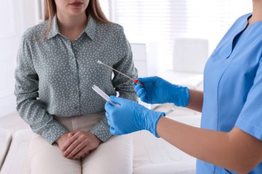 Doktor, klinikteki kadından cinsel yolla bulaşan hastalık testi için örnek alıyor.