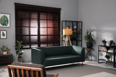 Rahat kanepe ve yeşil çiçekleri olan şık bir oturma odası.