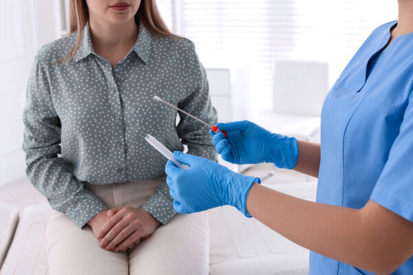 Doctor taking sample for STD testing from woman in clinic, closeup