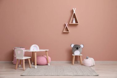 Mobilyaları, oyuncakları ve pembe duvarları olan şirin bir çocuk odası.