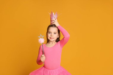 Sarı arka planda sihirli değneği olan pembe taçlı tatlı bir kız. Mesaj için yer var. Küçük prenses.