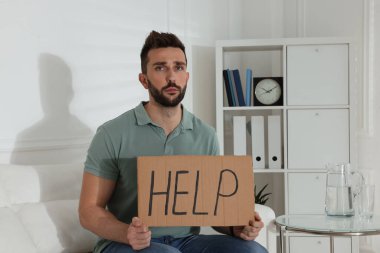 Mutsuz bir adam. Kapalı koltukta yardım yazısı var.