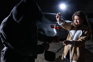 Hırsız gece dışarıda çantasını çalmaya çalışırken biber gazı kullanan bir kadın. Nefsi müdafaa