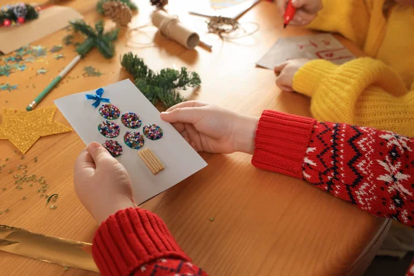 小孩在木制桌旁挂着漂亮的圣诞贺卡 特写镜头 — 图库照片