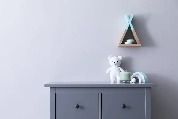 Child\'s toys on chest of drawers near light grey wall indoors