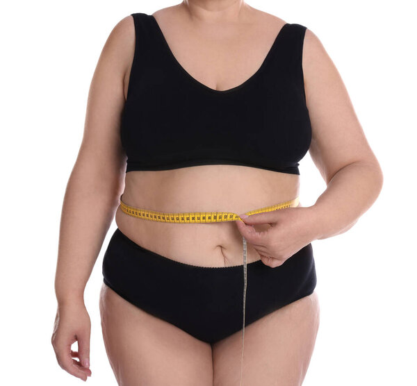 Overweight woman in underwear measuring waist with tape on white background, closeup
