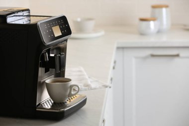 Modern elektrikli espresso makinesi. Mutfaktaki beyaz mermer tezgahta bir fincan kahve.
