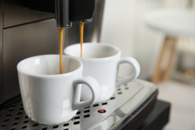 Espresso makinesi arka planda bulanık fincanlara kahve dolduruyor, yakın plan. Metin için boşluk