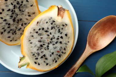 Lezzetli kesilmiş ejderha meyvesi tabağı (pitahaya) ve mavi ahşap masa üzerinde kaşık, düz yatıyordu