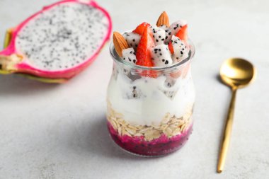 Çubuklu granola kavanozu, beyaz masada yoğurt ve çilek.