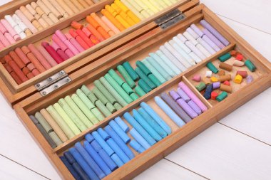 Beyaz ahşap masadaki kutuda yumuşak pastel renkler. Çizim malzemesi