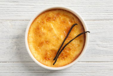 Lezzetli creme brulee ve vanilyalı çubuklar beyaz ahşap masa, üst manzara