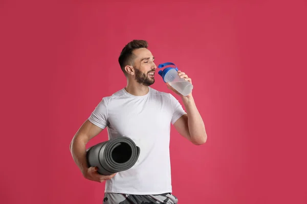 Hombre Guapo Con Esterilla Yoga Bebiendo Agua Sobre Fondo Rosa — Foto de Stock
